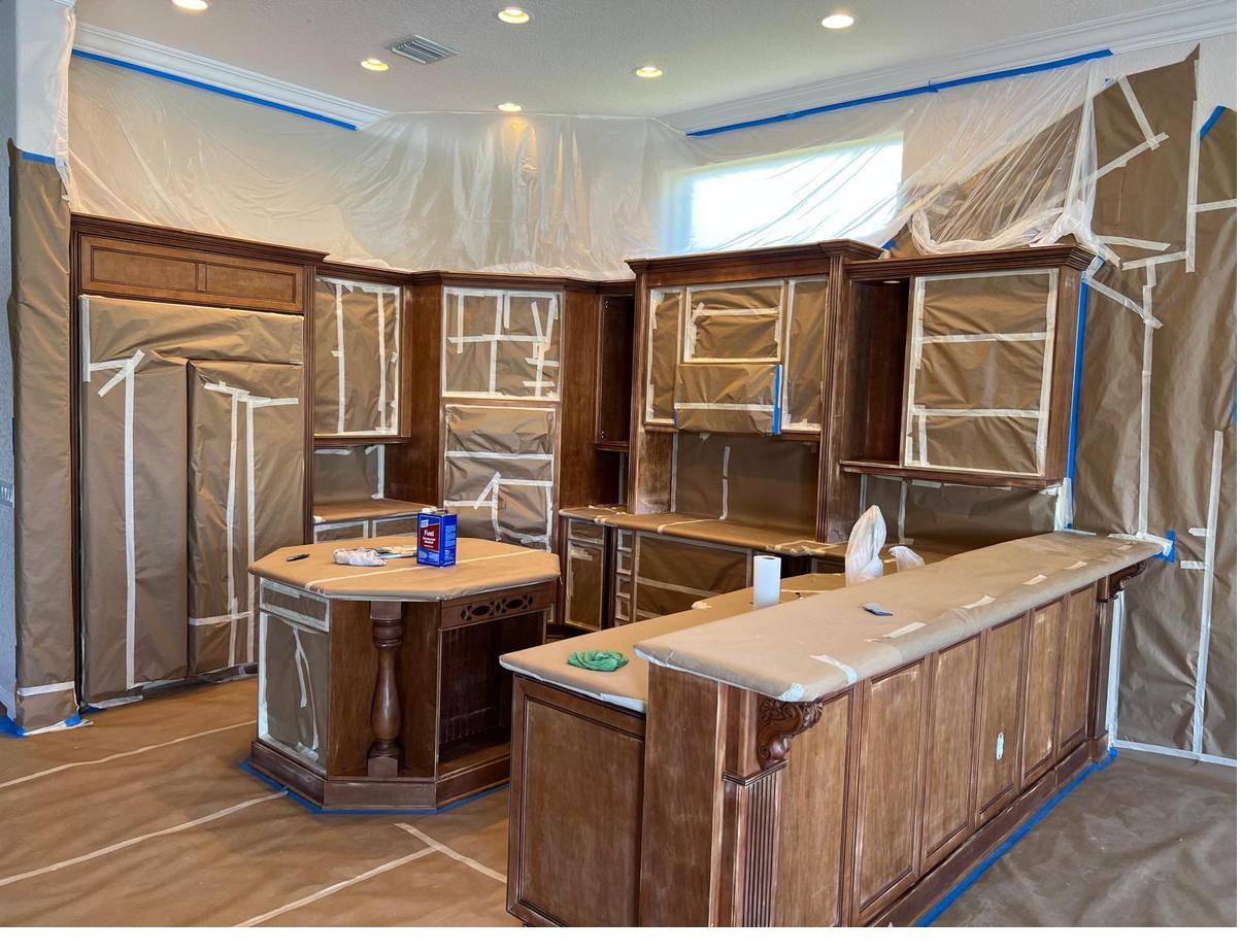 Kitchen with original dark wood cabinets, fully masked and protected before refinishing